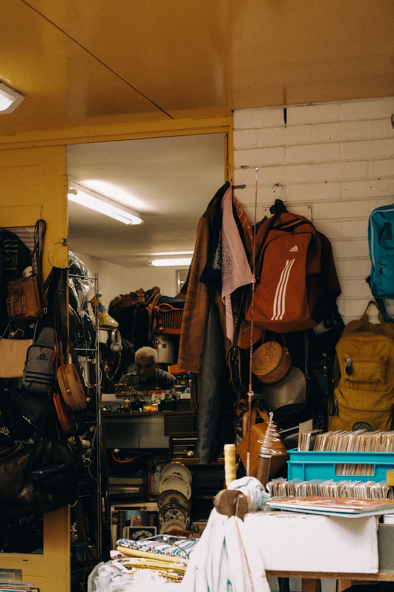 A secondhand shop owner among the pieces on the rack